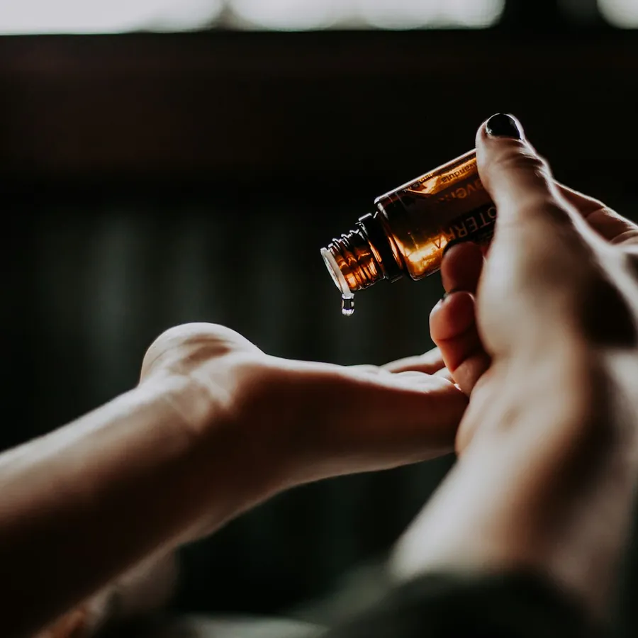 Hands dropping oil from a dropper