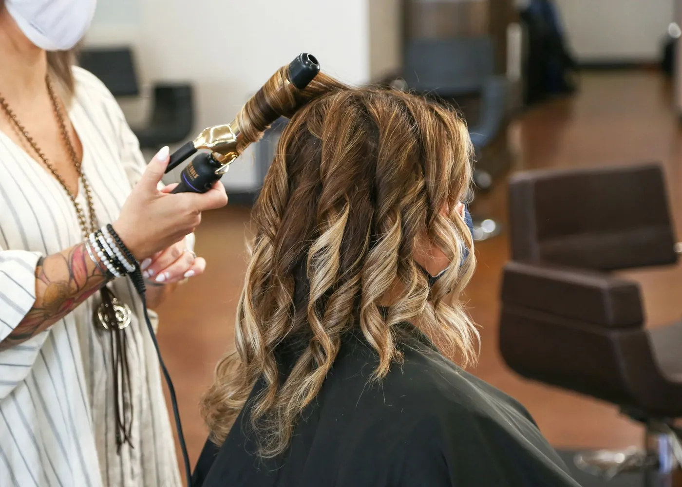 A stylist curling glossy hair